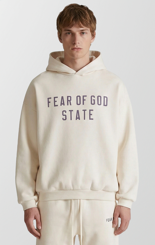A solid-colored streetwear hoodie with a relaxed fit, dropped shoulders, and a small rubber brand label on the top of the hood.