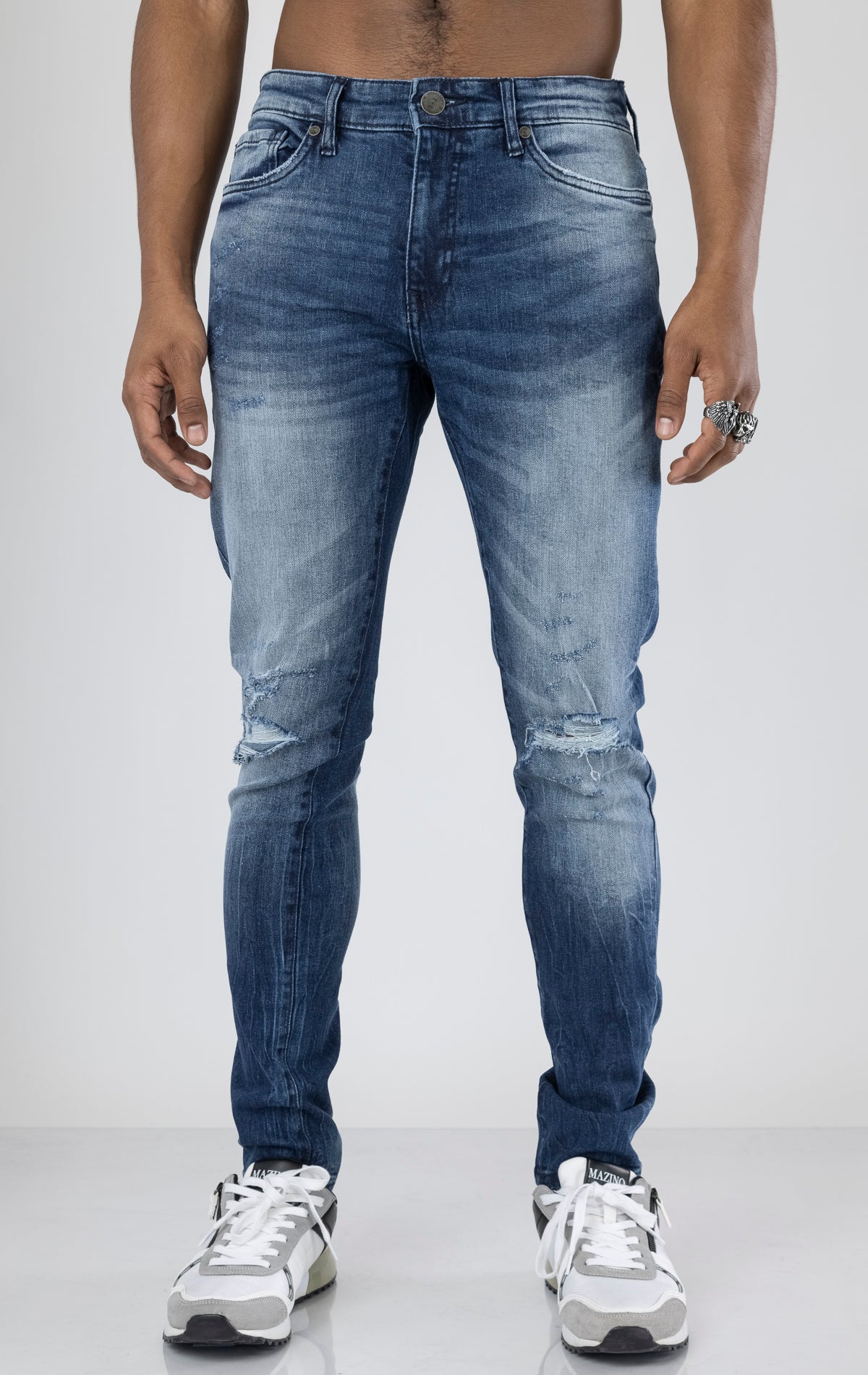 Men's ripped and distressed denim pants in a variety of washes. The pants feature a regular rise, tapered fit from the knee down, open rips at the knees, unique distressing details, and are made from 98% cotton with 2% lycra for stretch