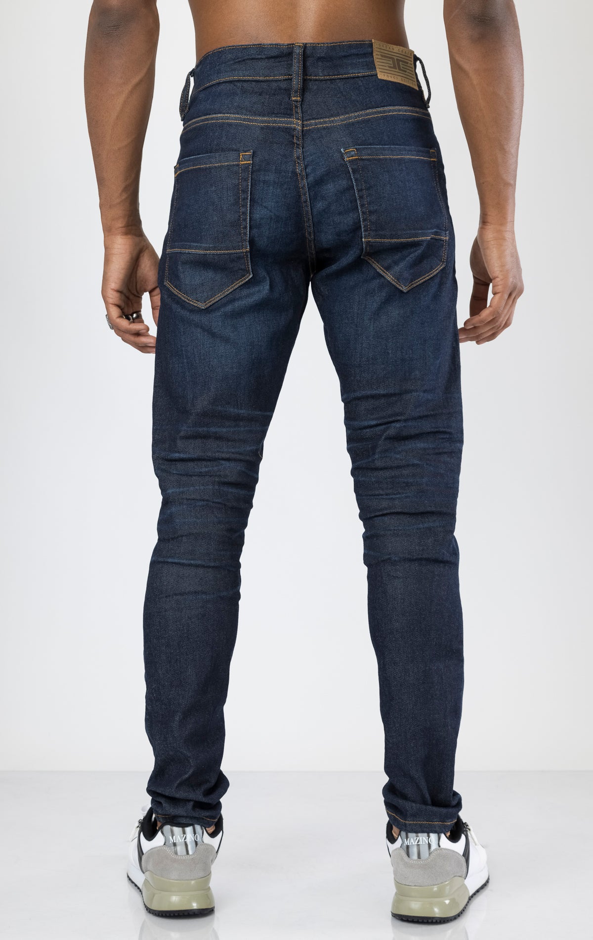 Men's Sean Slim Taper jeans in dark indigo. The jeans feature a regular rise waist, a comfortable fit from waist to thigh, a slim taper from knee to ankle, 3D baked wrinkles for texture, a raw denim look, and are made from a super stretch fabric blend (35% Cotton, 30% Polyester, 34% Tencel and 1% Elastane).