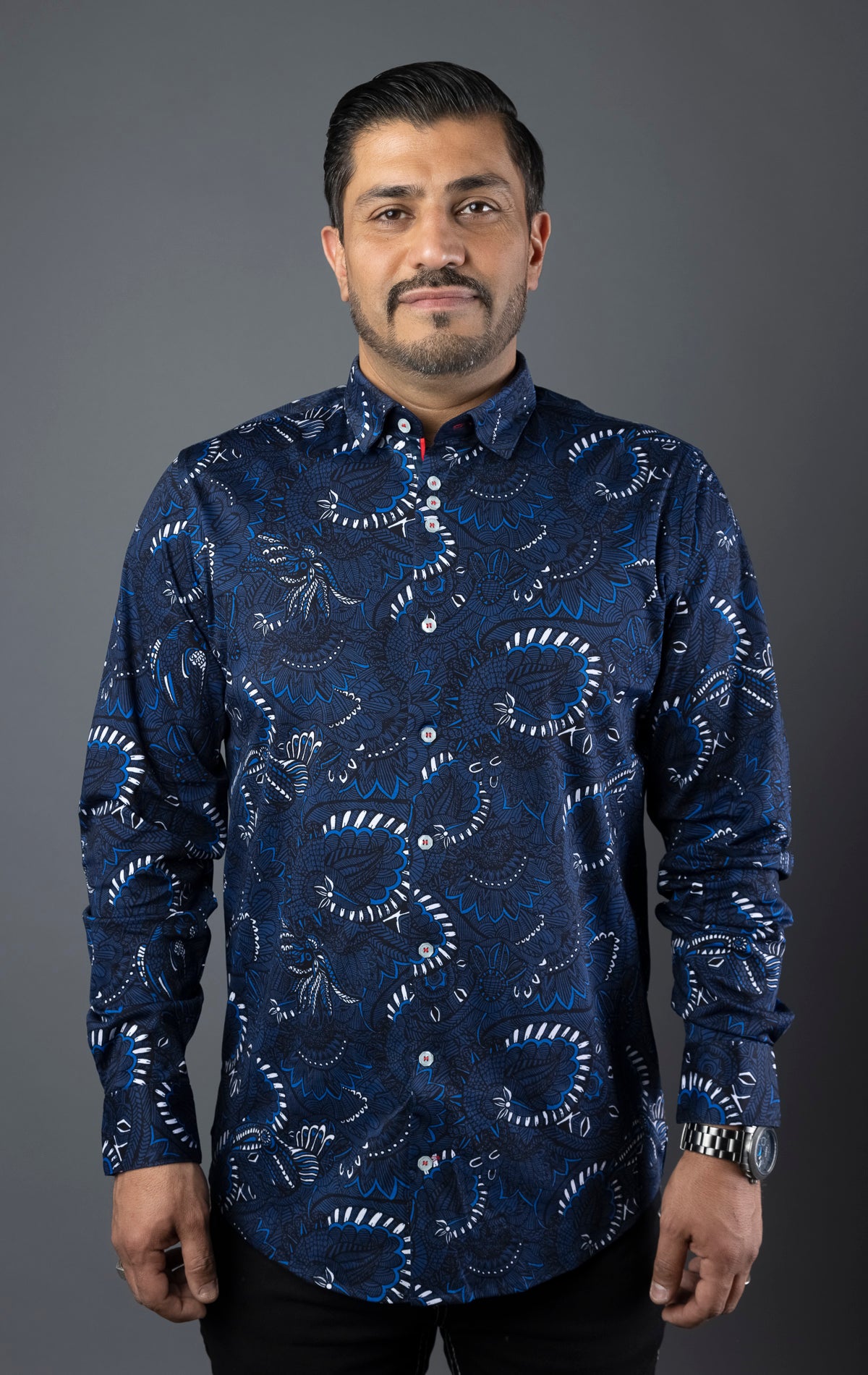 Close-up of a modern-fit dress shirt featuring an angled buttonhole, three buttons grouped together on the front placket, multiple embroidery details, and an elegant ceramic button on the sleeve placket. Canadian designed with performance stretch cotton fabric.