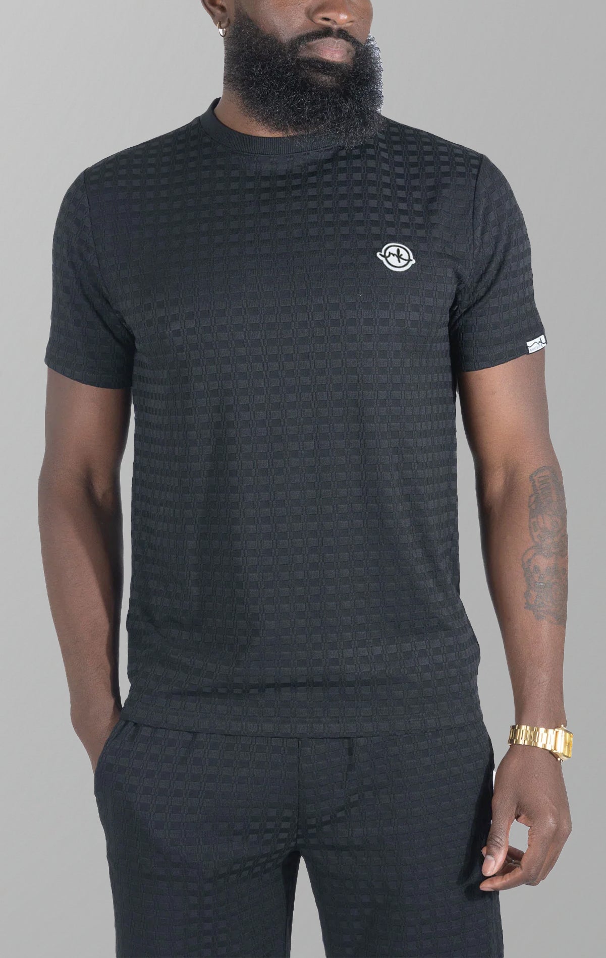 Black Modena Knit Tee. Made from a high-quality blend of 95% cotton and 5% spandex for a soft and comfortable feel. Features a unique embossed jacquard fabric with colored blocking for a textured and stylish look.  This tee is pre-shrunk and true to size.