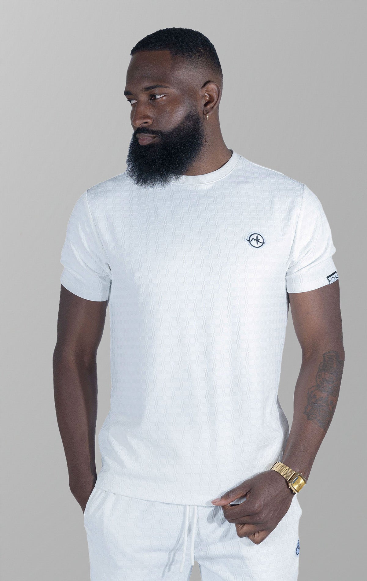 White Modena Knit Tee. Made from a high-quality blend of 95% cotton and 5% spandex for a soft and comfortable feel. Features a unique embossed jacquard fabric with colored blocking for a textured and stylish look.  This tee is pre-shrunk and true to size.
