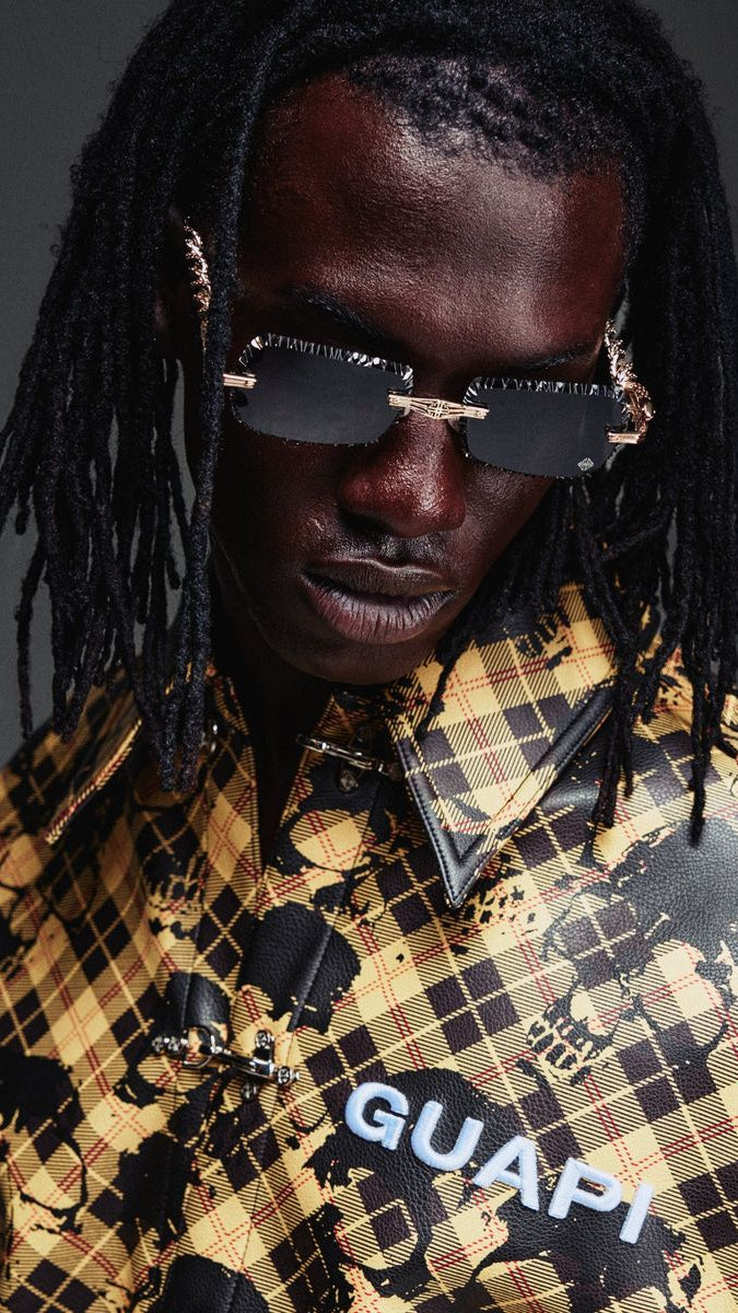 Person wearing sunglasses and a patterned shirt with 'GUAPI' branding.