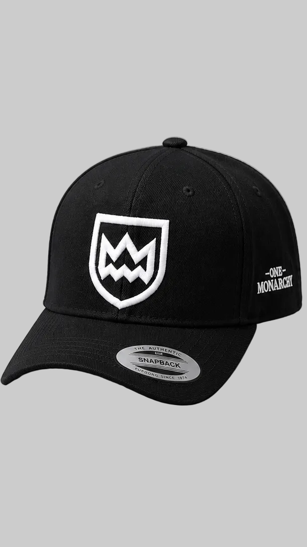 A black baseball cap with a white embroidered shield logo on the front and 'ONE MONARCH' text on the side, shown against a solid gray background.