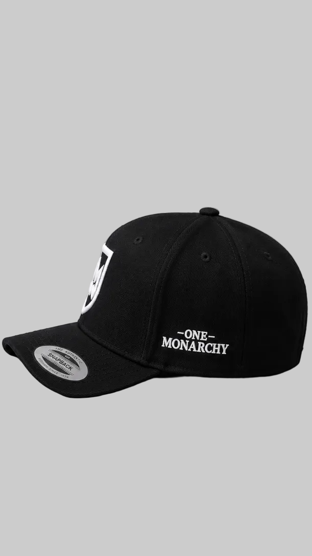 A black baseball cap with white embroidered text reading 'ONE MONARCHY' on the side and a white shield logo on the front, shown against a solid gray background.