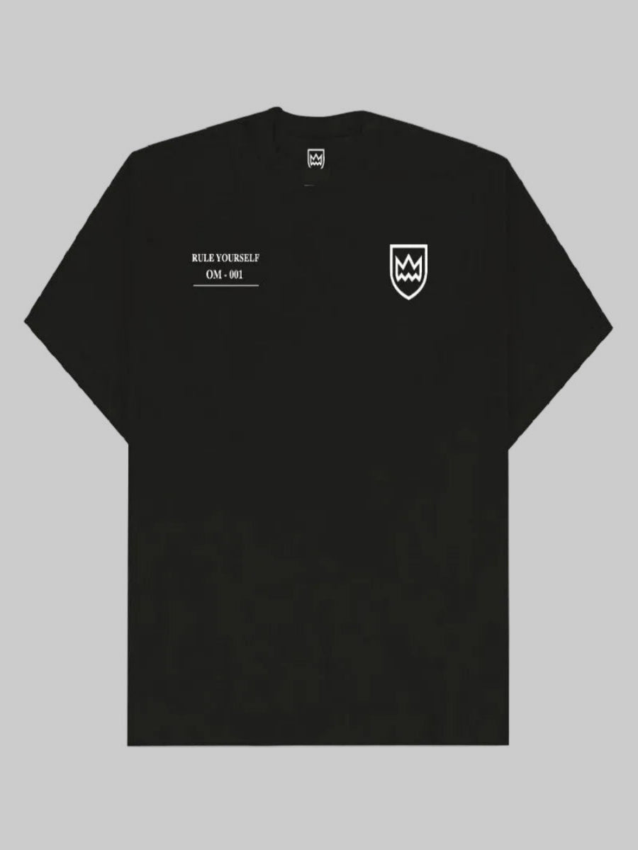 A black short-sleeve t-shirt with white printed graphics, featuring the text 'RULE YOURSELF OM-001' on the left chest and a shield logo on the right chest, displayed flat against a white background.