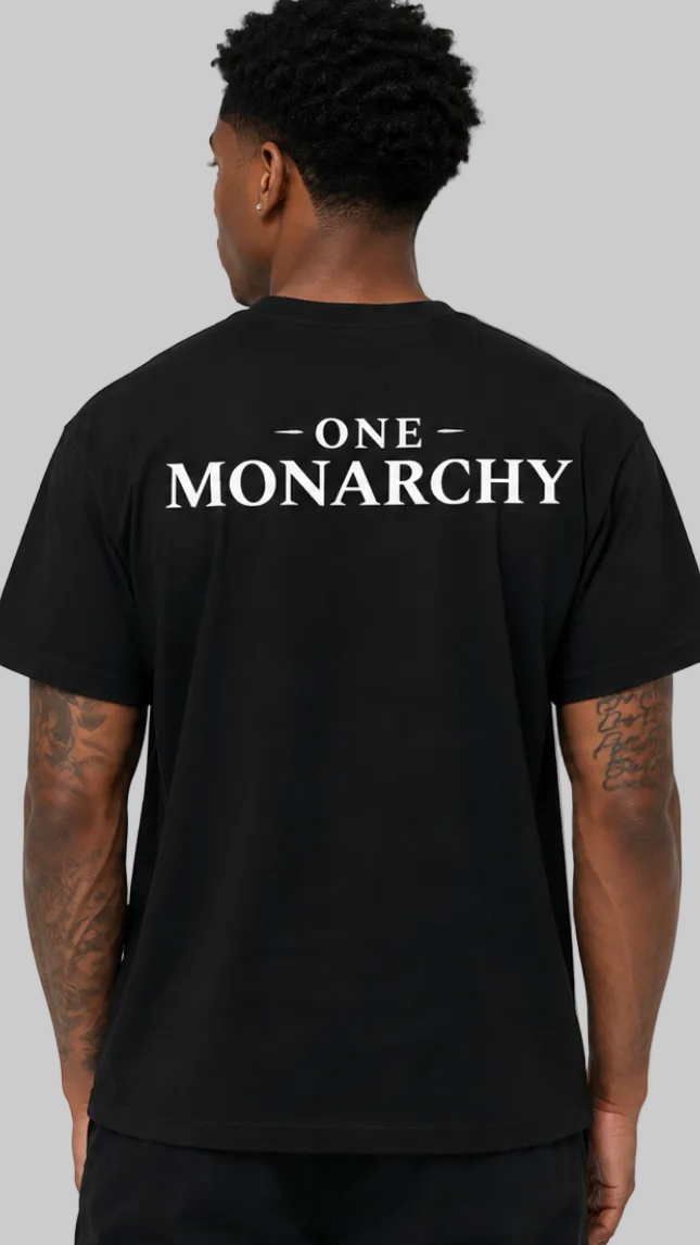 A man viewed from the back wearing a black t-shirt with 'ONE MONARCHY' printed in white across the upper back, set against a plain light gray background.