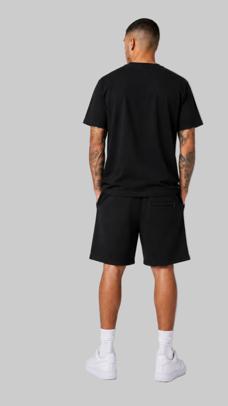 man modeling a black short-sleeve t-shirt and black shorts. The front view shows the shorts with a graphic of playing cards, while the back view shows the plain back of the t-shirt and shorts.