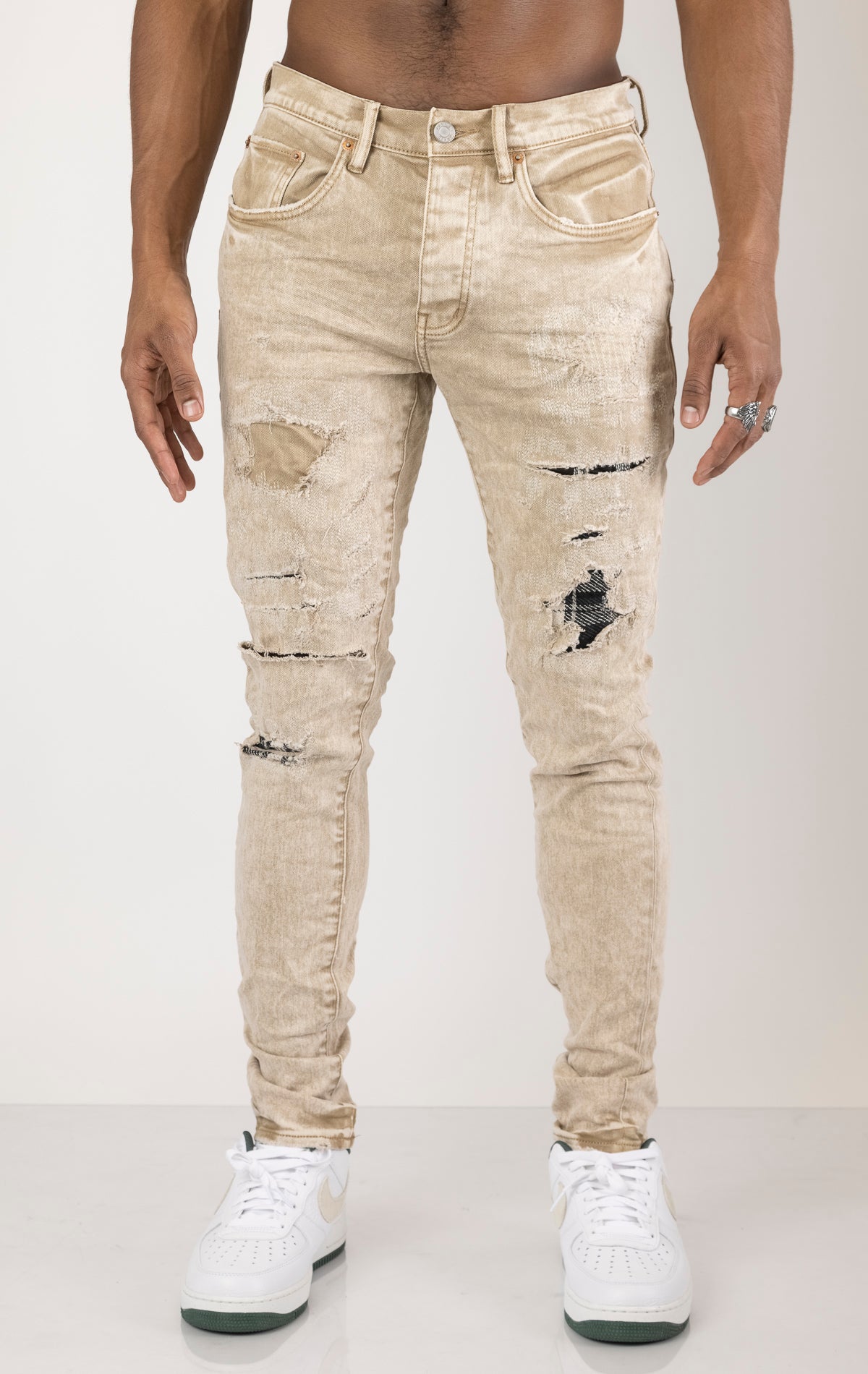 Beige Skinny Jeans with a contrasting plaid patch. Made from 98% cotton and 2% lycra. Features include a signature purple hangtag, lined back pockets and yoke for comfort and shape retention, reinforced belt loops, hidden back pocket rivets, and a classic button fly closure.  Please note: Due to the individual hand-finishing process, slight variations may occur, making each pair one-of-a-kind.