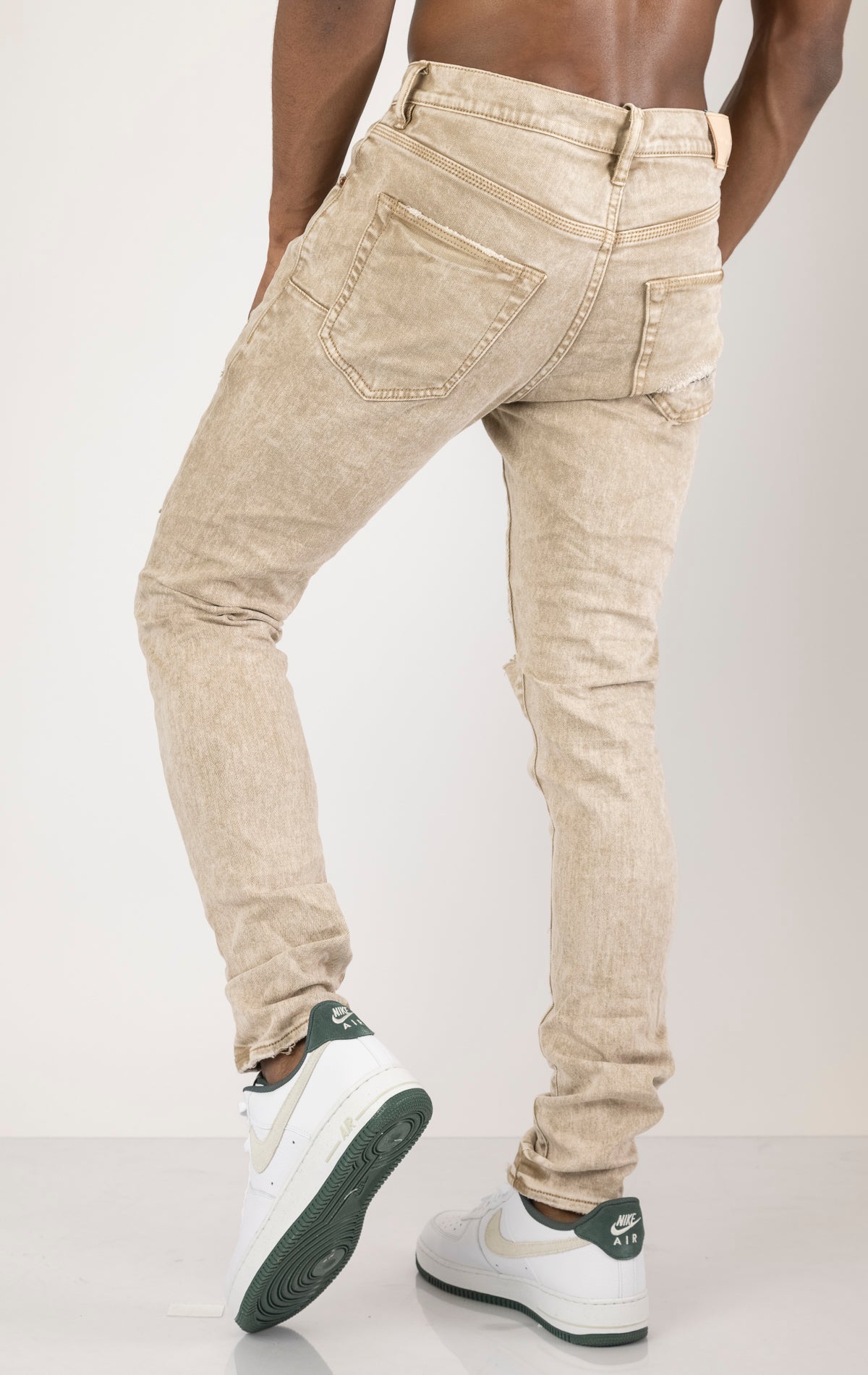 Beige Skinny Jeans with a contrasting plaid patch. Made from 98% cotton and 2% lycra. Features include a signature purple hangtag, lined back pockets and yoke for comfort and shape retention, reinforced belt loops, hidden back pocket rivets, and a classic button fly closure.  Please note: Due to the individual hand-finishing process, slight variations may occur, making each pair one-of-a-kind.