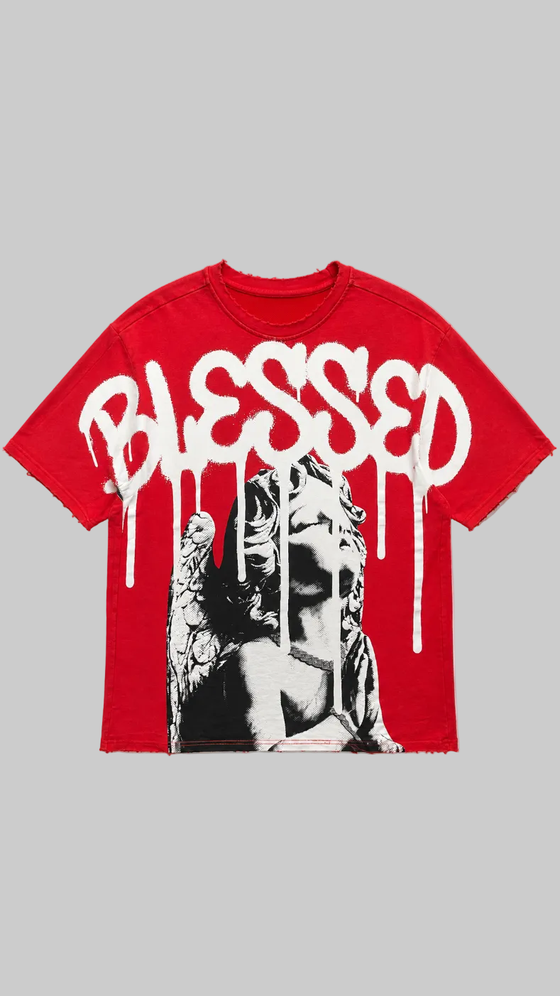 A red short-sleeve t-shirt with a distressed, frayed hem, featuring a large white spray-paint style graphic that reads 'BLESSED' with dripping paint over a black and white illustration of a winged female figure.