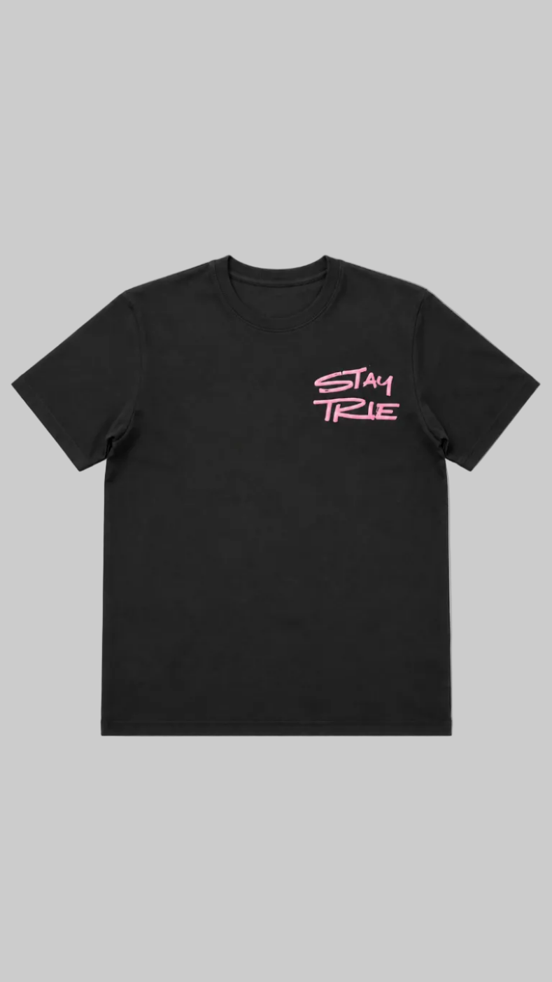 A black short-sleeve crewneck t-shirt with the words 'STAY TRUE' printed in pink script on the left chest, displayed against a light gray background.