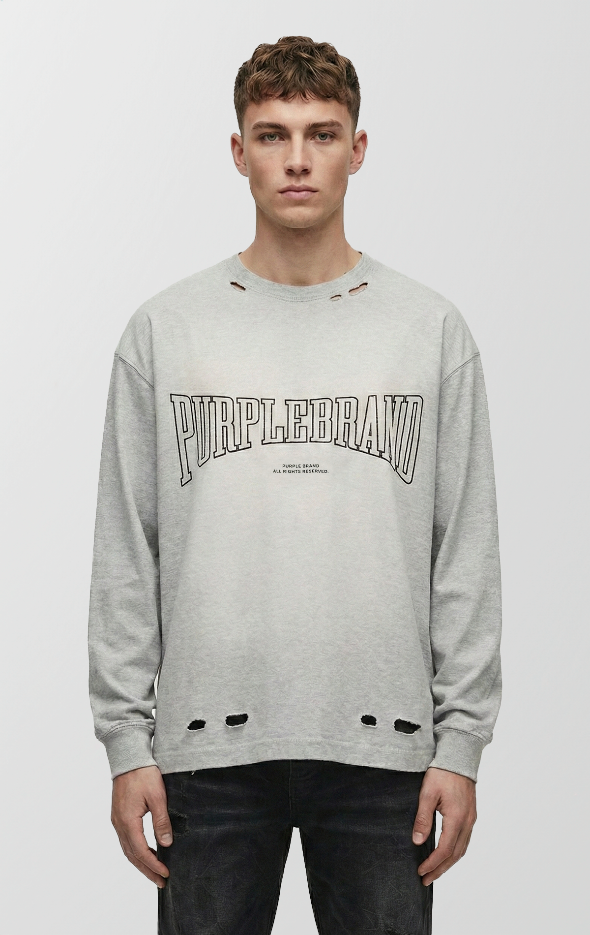 A heather-grey long-sleeve t-shirt with a relaxed fit, featuring black block lettering on the chest with a textured, cracked finish.