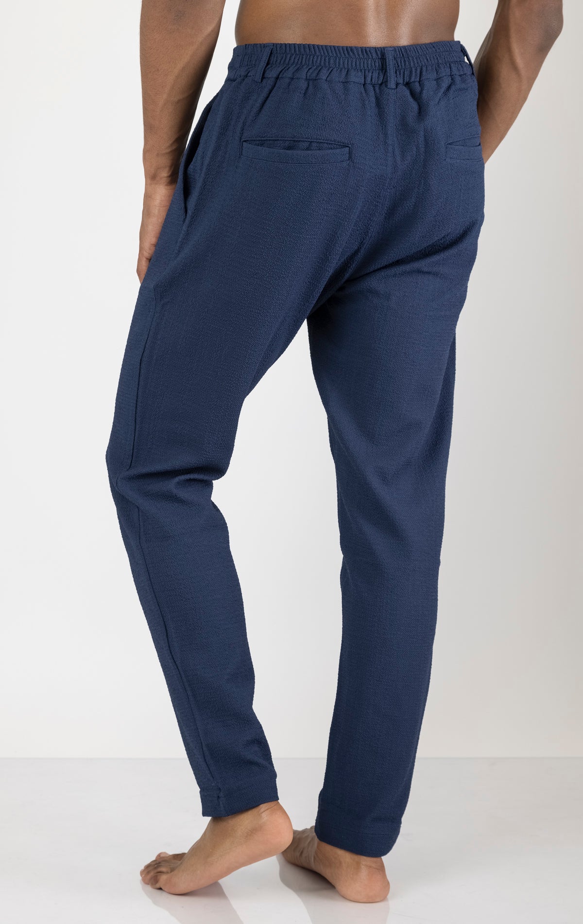 Men's front pleated waffle pants in navy. The pants are made from a textured waffle fabric (95% cotton, 5% elastane) and feature a relaxed fit, front pleats, and a comfortable elastic waistband.