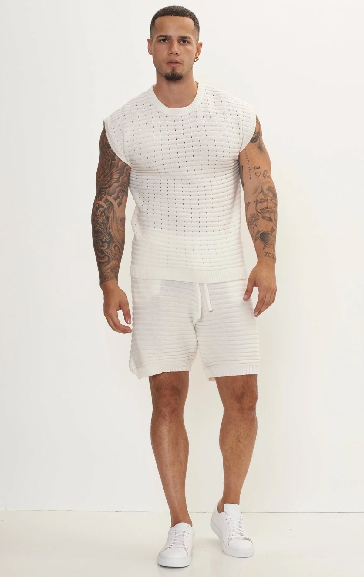 Men's white eyelet short sleeve knit top and shorts set in a variety of colors. The set is made from a soft and breathable knit fabric (50% viscose, 50% polyamide) and features a relaxed-fit top with eyelet detailing on the short sleeves and comfortable shorts with an elastic waistband.