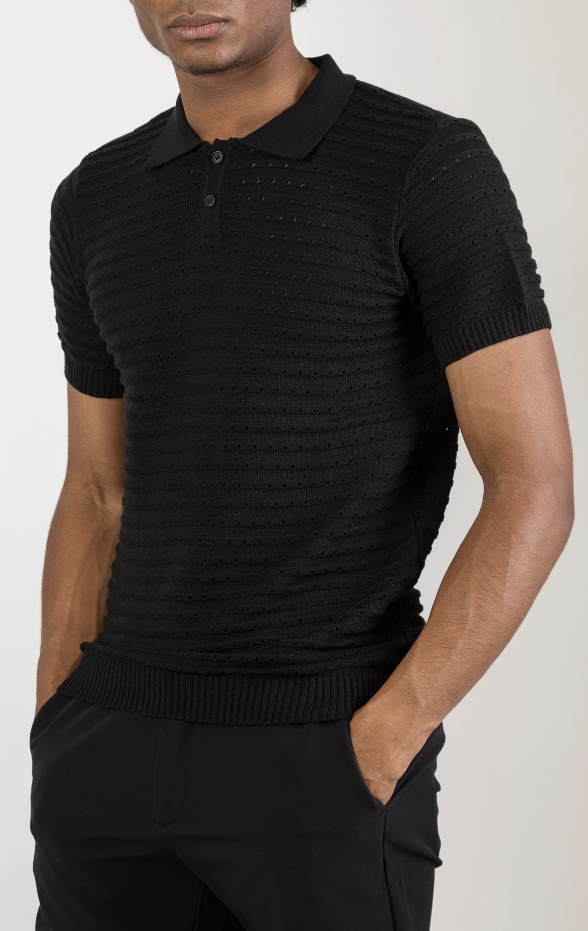 Men's eyelet short sleeve polo tee in Black . The shirt is made from a soft and breathable fabric (50% viscose, 50% polyamide) and features a classic polo collar, short sleeves, and delicate eyelet detailing along the sleeves.