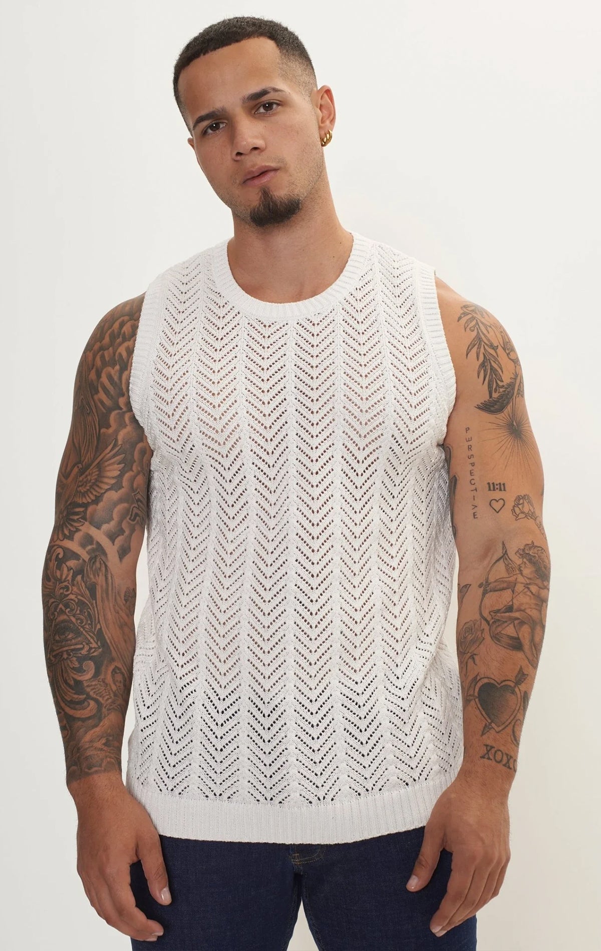 Men's knit muscle fit tank top in off white. The tank top is made from a 50% cotton, 50% acrylic blend and features a muscle fit cut, sleeveless construction, and a textured knit fabric.