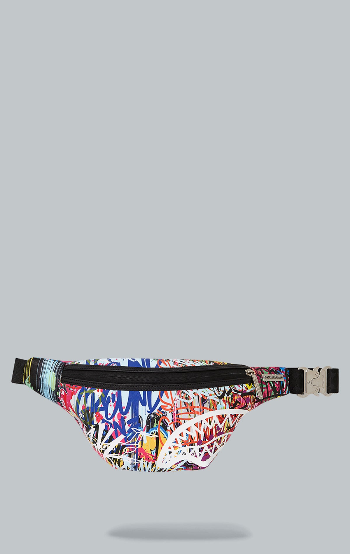 Sprayground Lower East Side Savvy Crossbody in black faux leather. The bag features a compact design, an adjustable double-sided VSM strap for comfortable wear, a red zippered pocket with metal buckle hardware, and dimensions of 7" x 1.5" x 15"