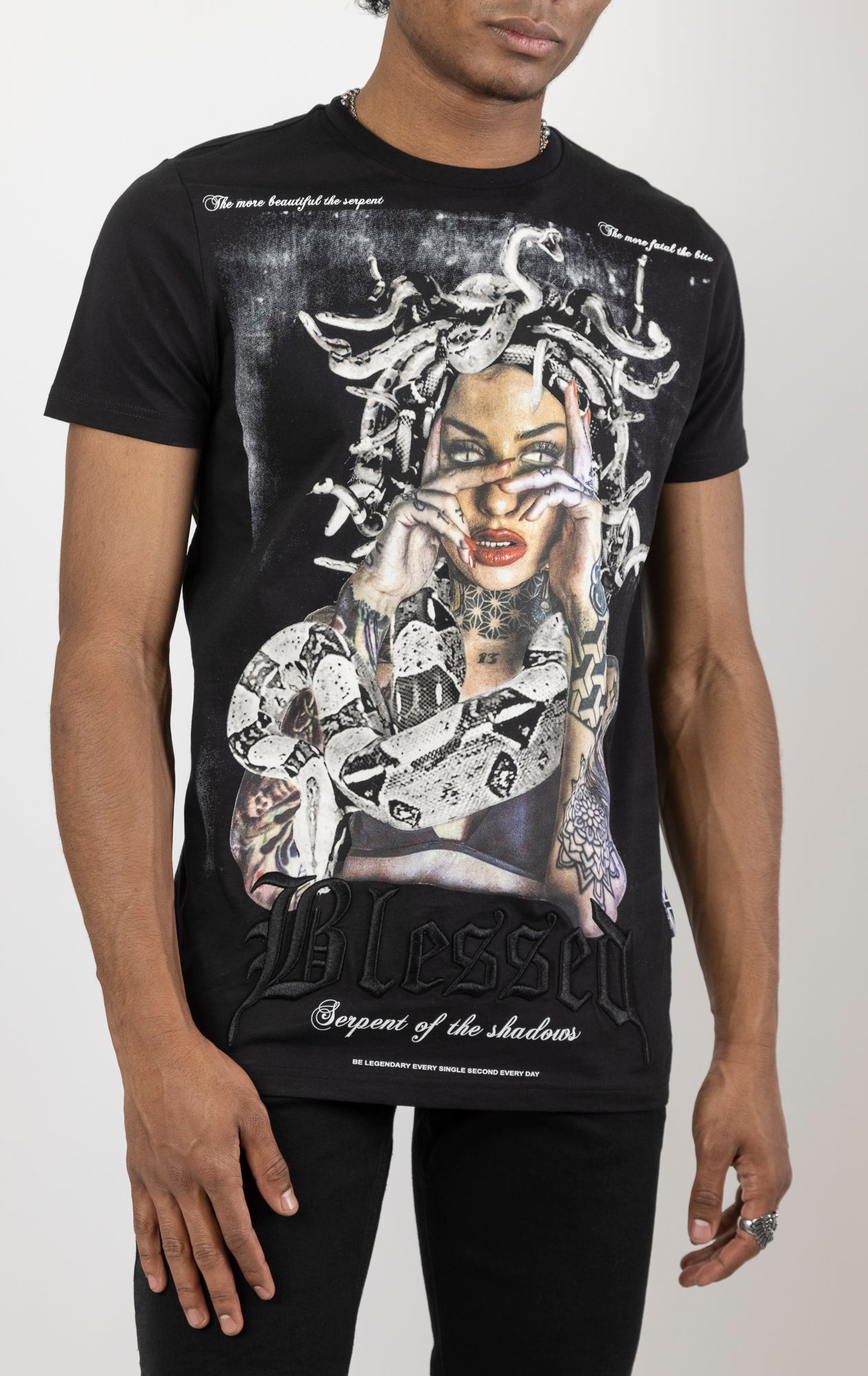Men's regular fit t-shirt in black. The shirt features a slightly elongated sleeve, a fitted neckline, and a straight body. It has a "Serpent of the Shadows" front print with 3D embroidery.  Made from 100% cotton jersey (190gsm).  A "blessed" slogan is printed on the inner neck binding and a woven side seam tab with "blessed" is also included.