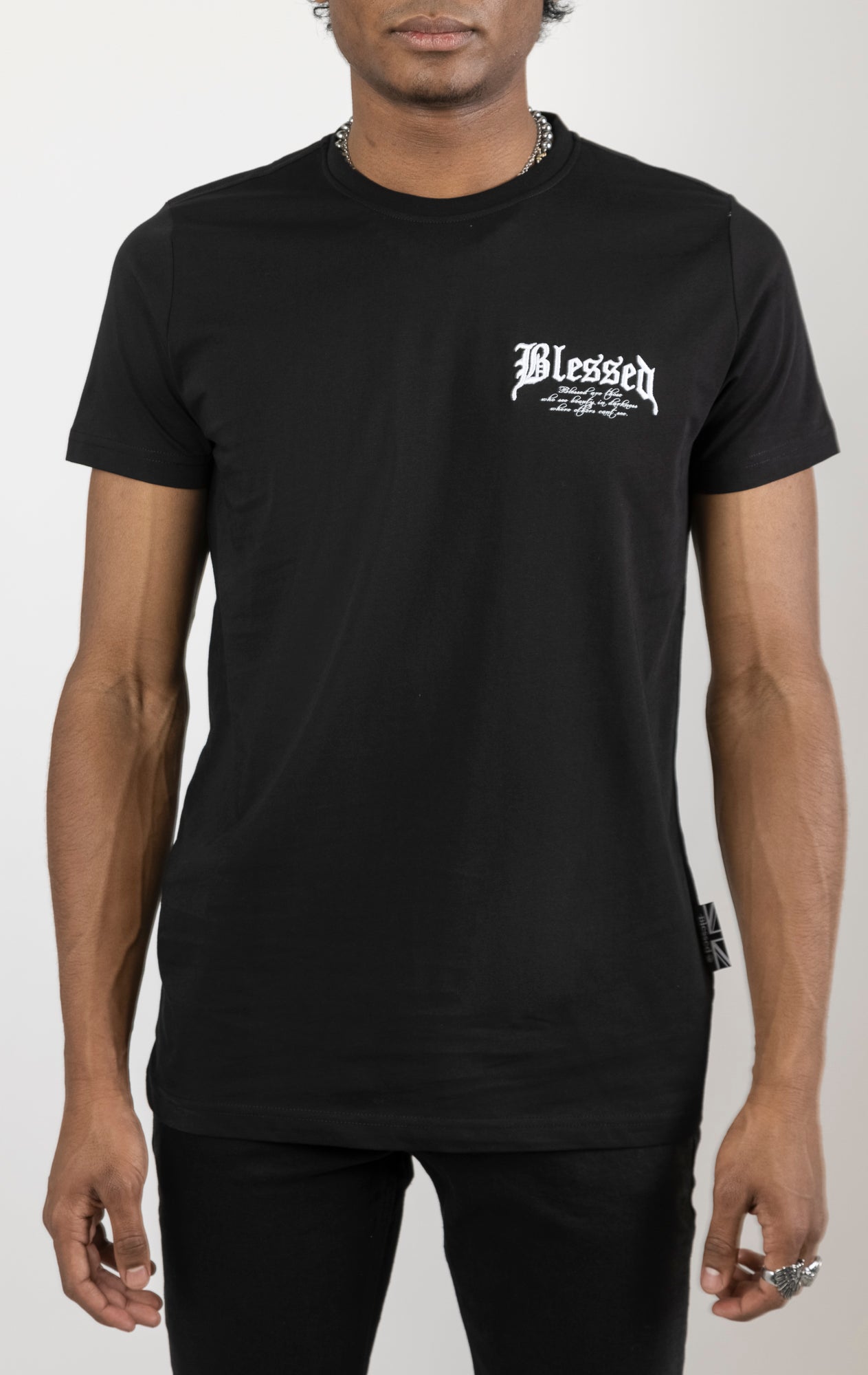 Men's regular fit t-shirt in black. The shirt features a slightly elongated sleeve, a fitted neckline, and a straight body. It has "Blessed with Beauty" printed on the front and back with 3D embroidery. Made from 100% cotton jersey (190gsm). A "blessed" slogan is printed on the inner neck binding and a woven side seam tab with "blessed" is also included.