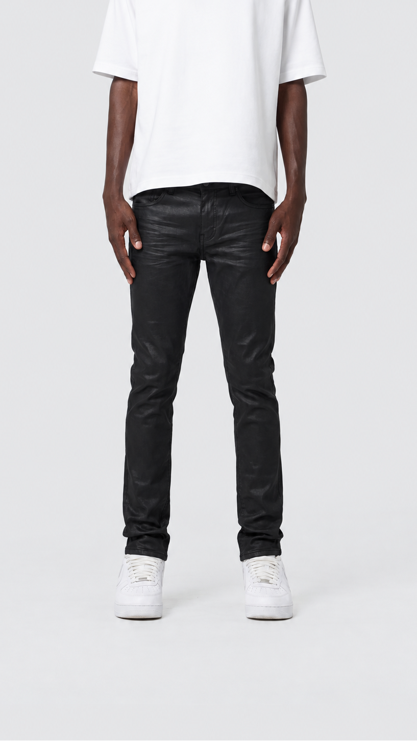 A model from the chest down wearing slim-fit black jeans, a white t-shirt, and white sneakers, standing against a light gray studio background.