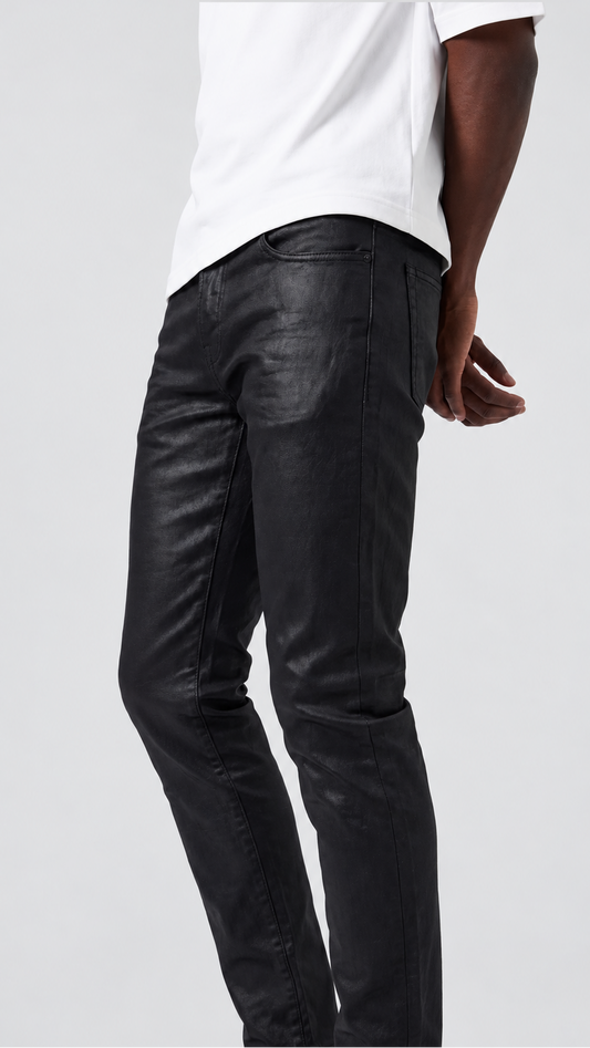 A person wearing slim black leather-look jeans and a white T-shirt, shown from the back against a light gray studio background.