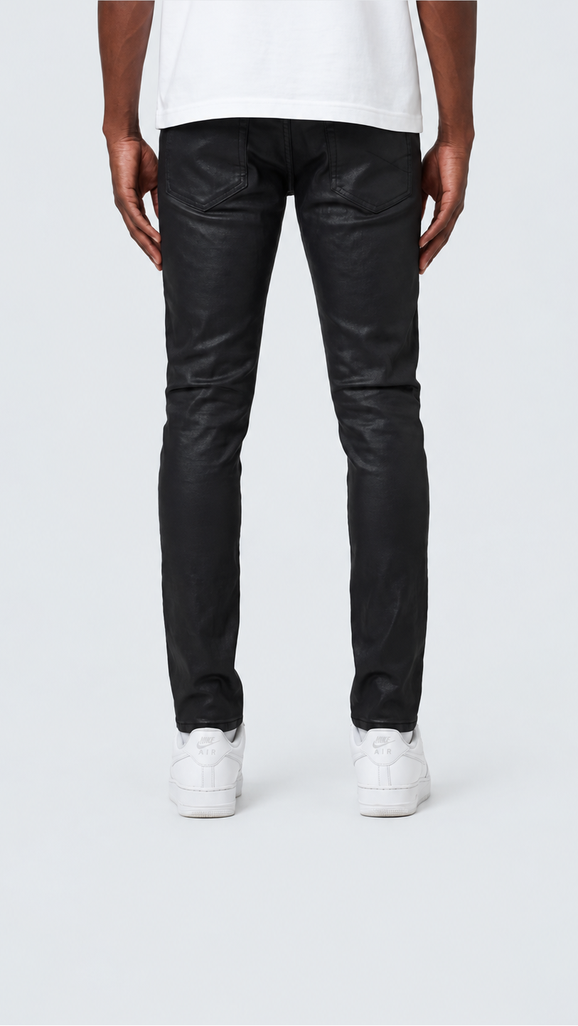A person shown from the back wearing slim black jeans, a white t-shirt, and white sneakers against a light gray studio background.