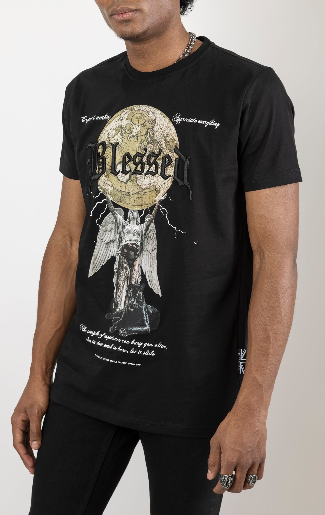 Men's regular fit t-shirt in a variety of colors. The shirt features a slightly elongated sleeve, a comfortable fit through the shoulders and body, and a "Weight of Expectations" front print with 3D embroidery.  Made from 100% cotton jersey (190gsm).  A "blessed" slogan is printed on the inner neck binding and a woven side seam tab with "blessed" is also included.